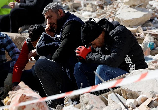 ভূমিকম্পে নিখোঁজ স্বজনদের খবরের অপেক্ষায় ধ্বংসস্তূপের ওপর বসে আছেন কয়েকজন। কিরিখান, তুরস্ক