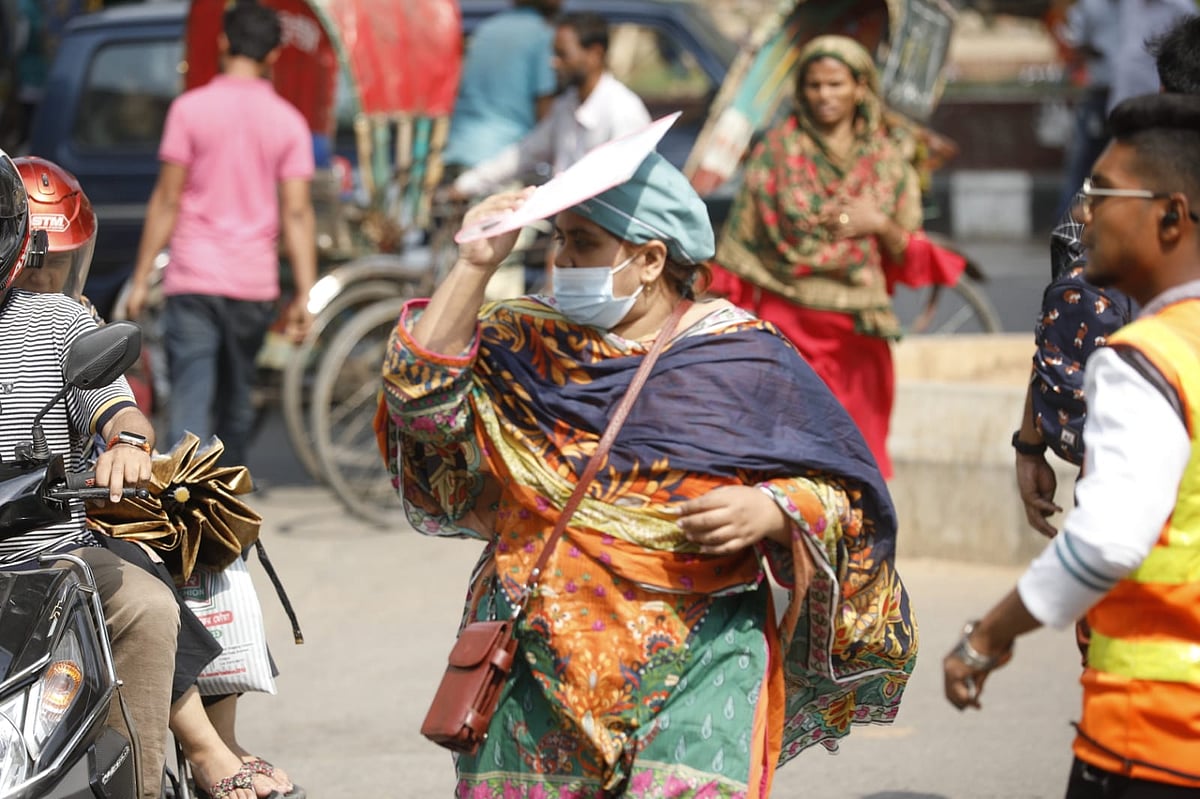 রোদের তাপ থেকে নিজেকে রক্ষায় হাতের কাগজ দিয়ে মাথা ঢেকে গন্তব্যে রওনা হয়েছেন এক পথচারী। ১১ এপ্রিল, শাহবাগ, ঢাকা