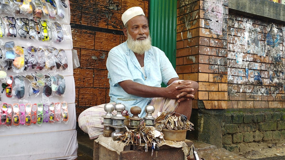 সিলেট নগর ভবনের সামনে ক্রেতার অপেক্ষায় বসে ছিলেন চাবি বানানোর কারিগর আহমদ আলী। শুক্রবার বেলা একটার দিকে