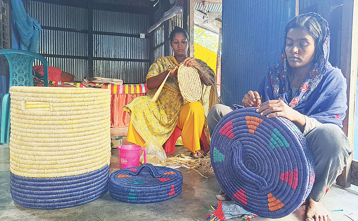 নিজ বাড়িতে ছন ও খেজুরপাতা দিয়ে আকর্ষণীয় পণ্য তৈরির কাজে ব্যস্ত রুম্পা মাখাল ও তাঁর দলের সদস্যরা
