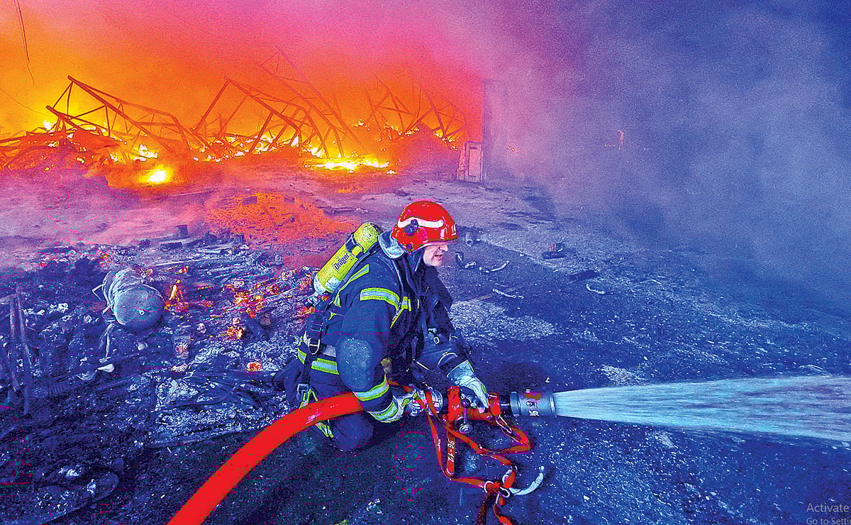 রাশিয়ার ক্ষেপণাস্ত্র হামলার পর জ্বলছে একটি গুদাম। নেভানোর কাজ করছেন এক অগ্নিনির্বাপণকর্মী