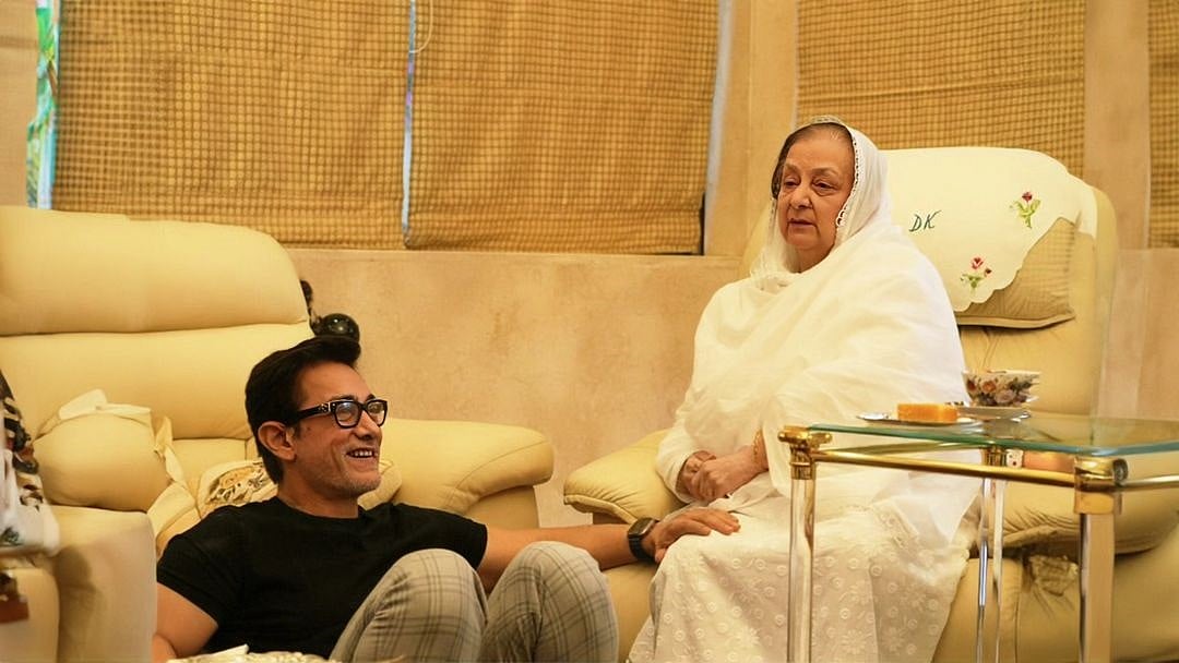 সোফায় বসে আছেন সায়রা বানু; তাঁর পায়ের পাশে মেঝেতে বসে আছেন আমির খান