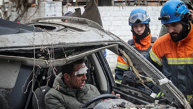রাশিয়ার ক্ষেপণাস্ত্র হামলায় ব্যাপক ক্ষতিগ্রস্ত একটি আবাসিক ভবনের কাছে আহত এক ব্যক্তির সঙ্গে কথা বলছেন উদ্ধারকর্মীরা। খারকিভ, ইউক্রেন, ২ জানুয়ারি
