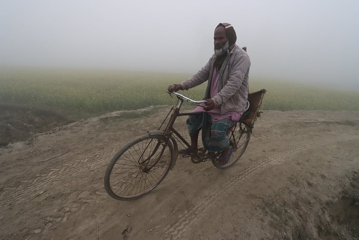 তীব্র শীত ও ঘন কুয়াশার মধ্যে কৃষি সরঞ্জাম সাইকেলে চাপিয়ে জমিতে কাজ করতে যাচ্ছেন কৃষক। বৈকুণ্ঠপুর এলাকা, রংপুর, ২৪ জানুয়ারি