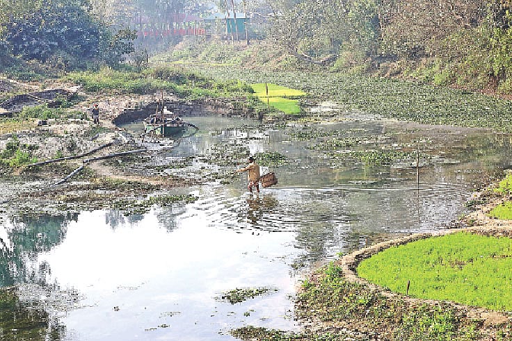 ফসলি জমি ঝুঁকিতে ফেলে নদী থেকে বালু তোলা হচ্ছে। হাঁটুপানি পেরিয়ে নদী পার হচ্ছেন এক ব্যক্তি। গত শনিবার সকালে বগুড়া সদর উপজেলার ধাওয়া কোলা গ্রাম এলাকায়