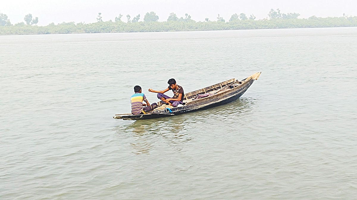 সুন্দরবনের শাকবাড়ীয়া নদীতে নৌকা ভাসিয়ে নদীর মধ্যে কাঁকড়া ধরার জন্য টোপ ফেলেছেন দুই জেলে। গত সোমবার সুন্দরবনের শাকবাড়ীয়া নদীর পাড়ে