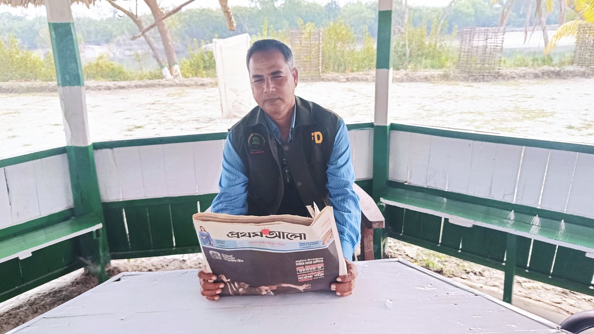 সুন্দরবনের কালাবগী ফরেস্ট স্টেশনে বসে পত্রিকা পড়ছেন বন কর্মকর্তা আবদুল হাকিম