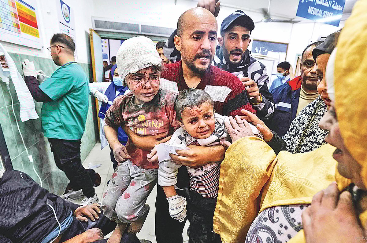 ইসরায়েলি বোমায় আহত দুই শিশুকে নিয়ে এক ফিলিস্তিনি নিরাপদ আশ্রয়ের সন্ধানে। গতকাল দক্ষিণ গাজায় আল-নাসর হাসপাতালে
