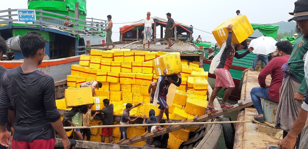 টেকনাফ স্থলবন্দরে নৌযান থেকে পণ্য খালাস করছেন শ্রমিকেরা। আজ রোববার বিকেলে