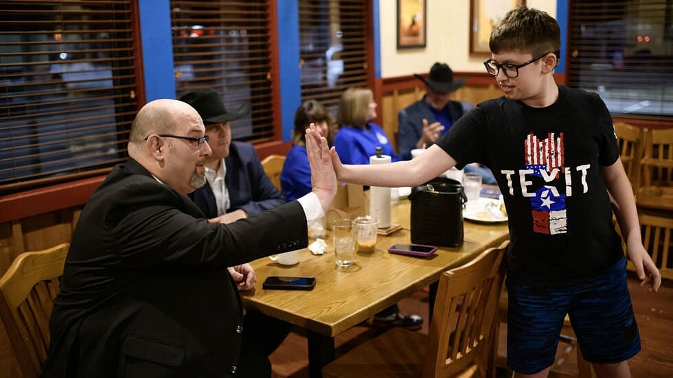 টেক্সিট লেখা টি–শার্ট পরা এক শিশুকে অভিনন্দন জানাচ্ছেন টেক্সাসের স্বাধীনতাকামী নেতা ড্যানিয়েল মিলার