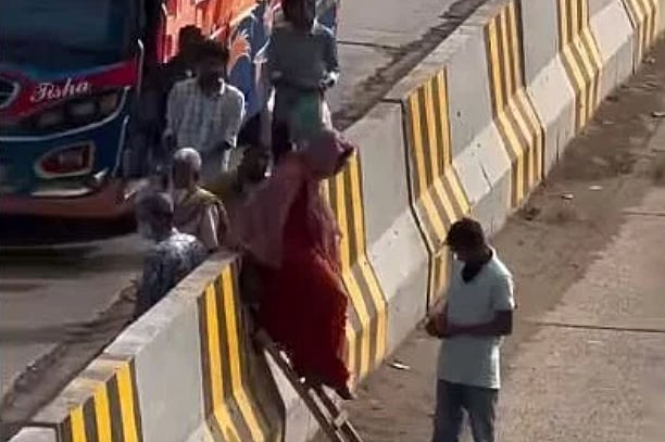 টাকার বিনিময়ে মই দিয়ে পথচারীদের সড়ক বিভাজক পার করা হচ্ছে।