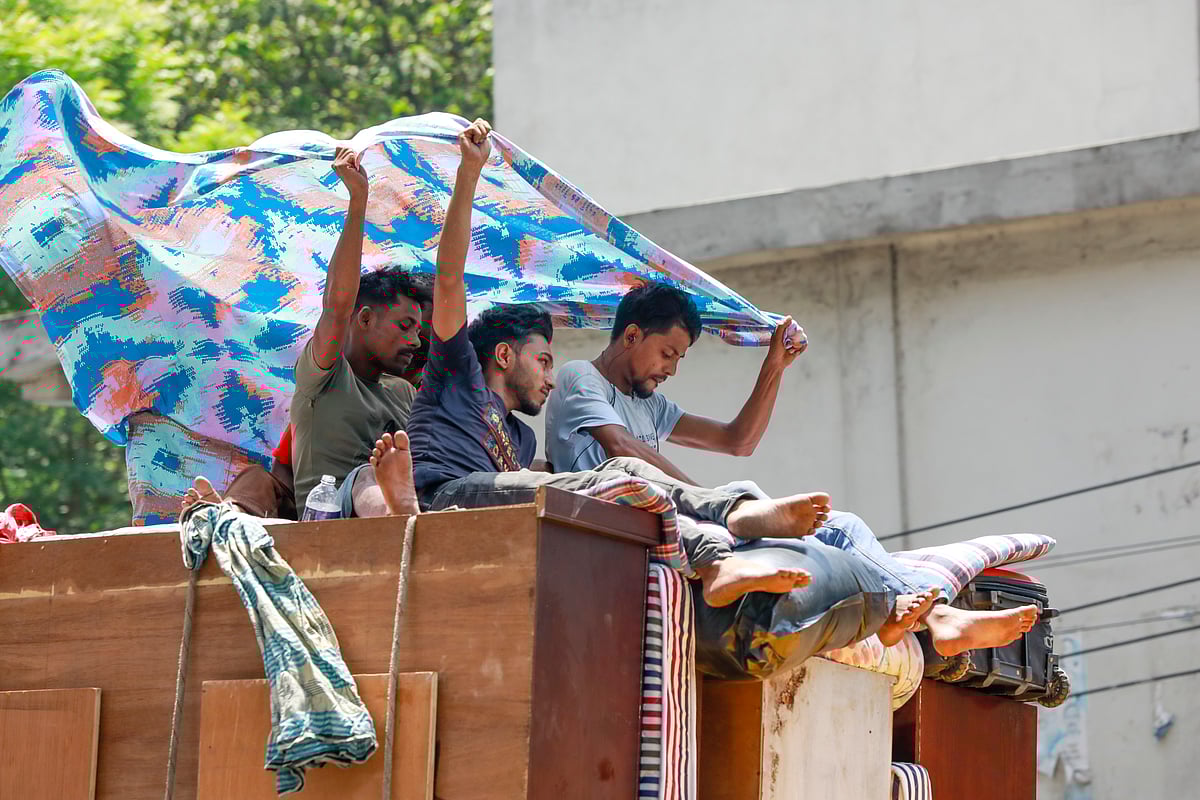 প্রচণ্ড গরমের মধ্যে ট্রাকের ওপর বাসা পরিবর্তনের মালামাল নিয়ে গন্তব্যে যাচ্ছেন মানুষ। বাংলামোটর এলাকা থেকে