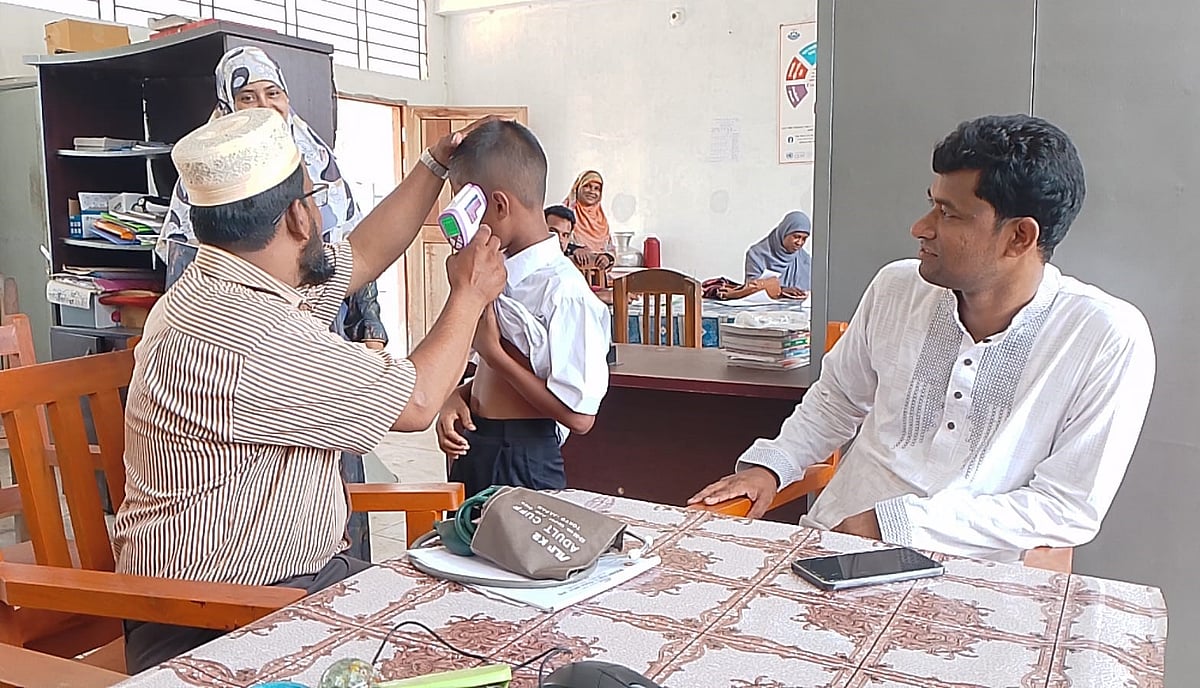 অসুস্থ হয়ে পড়া এক শিক্ষার্থীর তাপমাত্রা দেখছেন পল্লি চিকিৎসক। আজ সকালে হাতিয়ার  জনকল্যাণ শিক্ষা ট্রাস্ট হাইস্কুলে