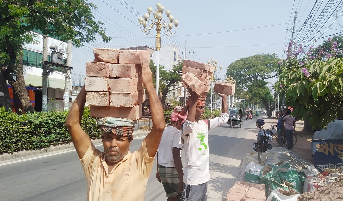 শ্রমিকেরা মাথায় ইট নিয়ে যাচ্ছেন। আজ মঙ্গলবার সকাল পৌনে ১০টার দিকে রাজশাহী নগরের ভদ্রা এলাকায়