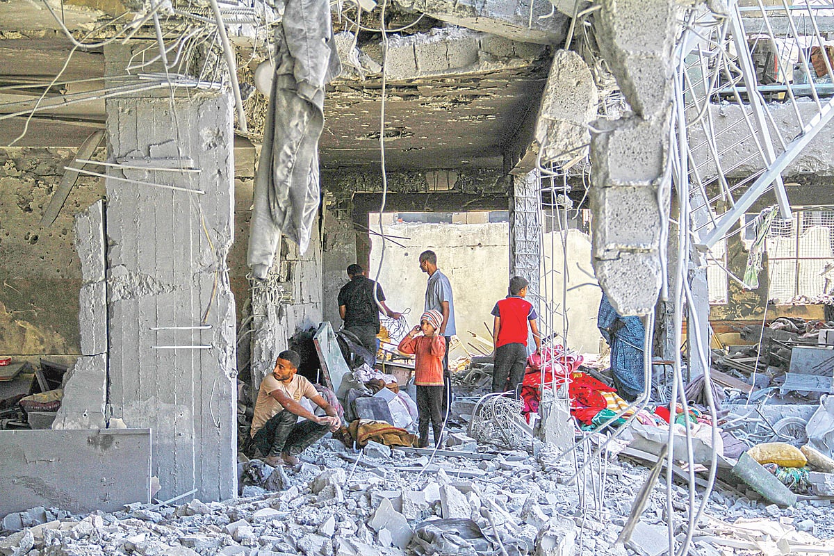 ইসরায়েলের হামলায় ধসে গেছে ভবন। ধ্বংসস্তূপে বসে আছেন কয়েকজন ফিলিস্তিনি। গতকাল গাজা উপত্যকার জেইতুনে