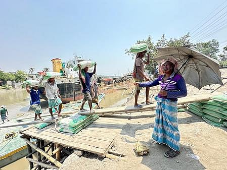 ট্রলার থেকে বস্তাভর্তি সিমেন্ট মাথায় করে আনছেন শ্রমিকেরা। পা পিছলে যেকোনো সময় ঘটতে পারে দুর্ঘটনা। গতকাল যশোরের নওয়াপাড়ায় ভৈরব নদের পাড়ে