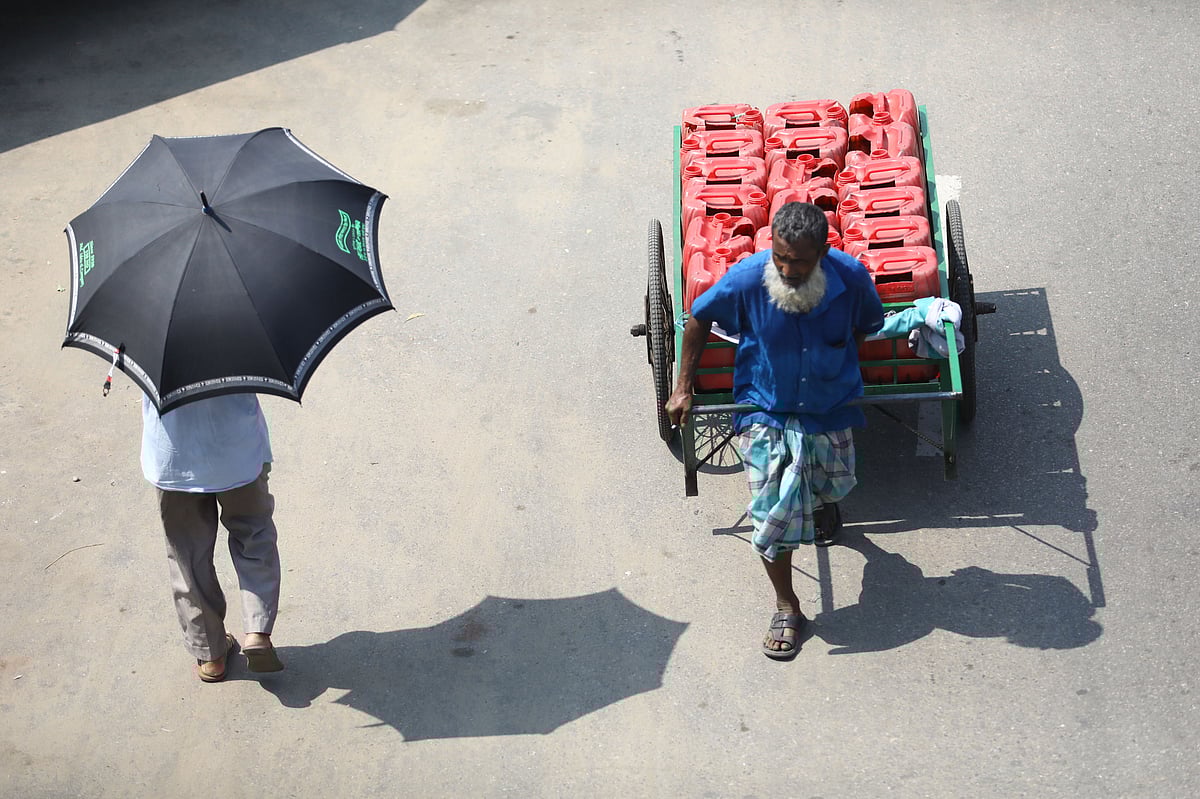 প্রখর রোদের মধ্যে ভ্যানে করে পানি নিয়ে যাচ্ছেন চালক। ছাতা মাথায় পথ চলছেন আরেকজন। হুমায়ুন রশীদ চত্বর, সিলেট