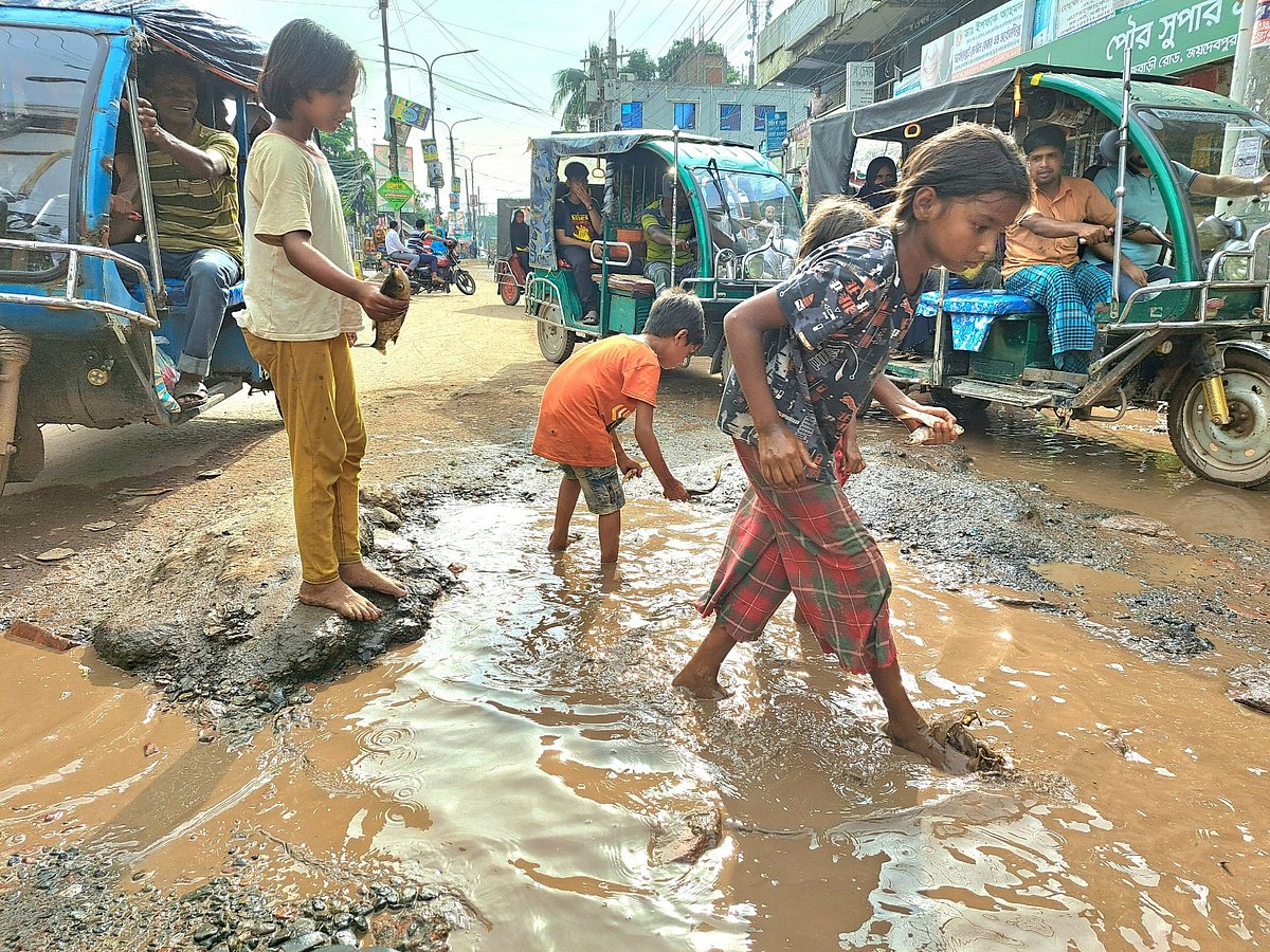 গাজীপুরে সড়কের গর্ত থেকে মাছ ধরছে শিশুরা। গাজীপুর পৌর মার্কেট এলাকায় গত বুধবার বিকেলে