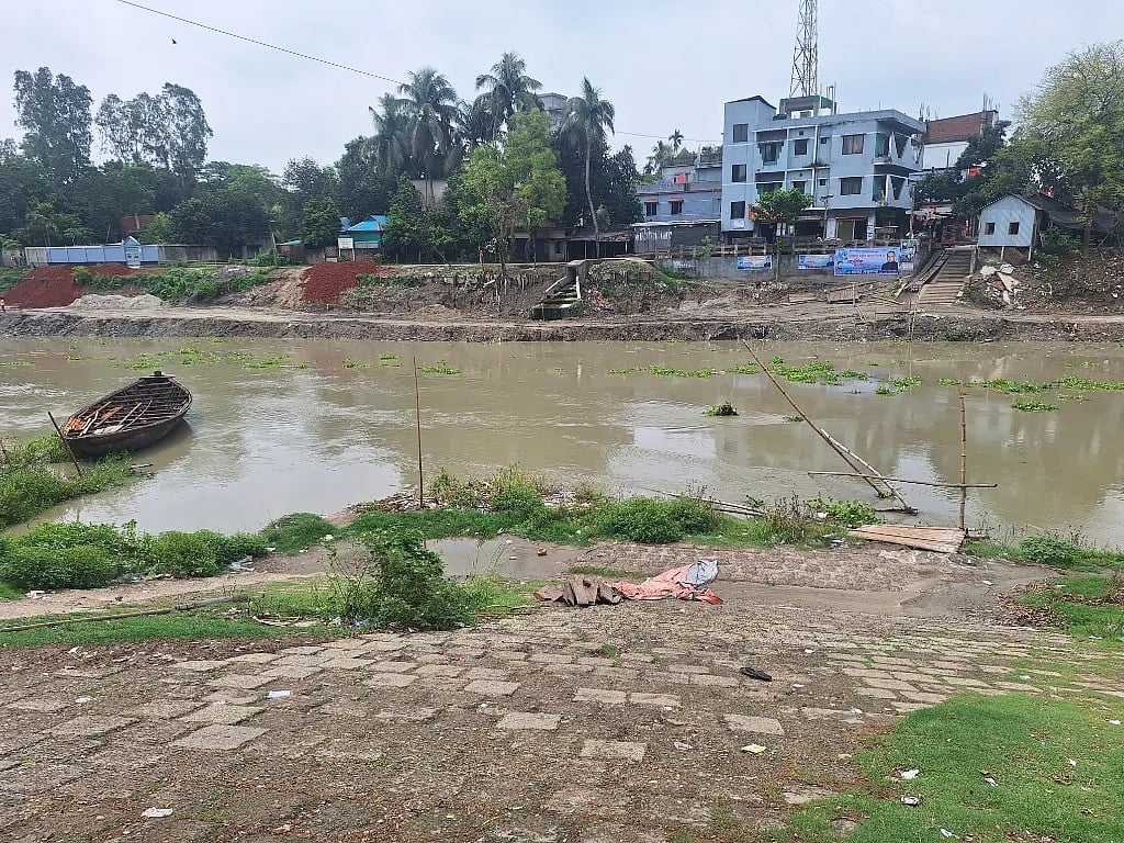 দেখে বোঝার উপায় নেই দুই দিন আগেও বাঁশের সাঁকো ছিল এখানে। এটি ভেঙে যাওয়ার পর নদ পারাপারে আজ নৌকা (বাঁ পাশে) প্রস্তুত করা হচ্ছে
