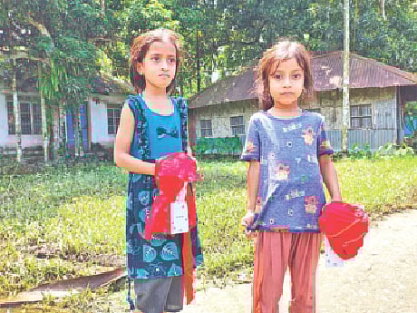 প্রথম আলো ট্রাস্টের উদ্যোগে দেওয়া নতুন পোশাক হাতে দুই শিশু। গতকাল দুপুরে বেগমগঞ্জ উপজেলার আলীপুরে