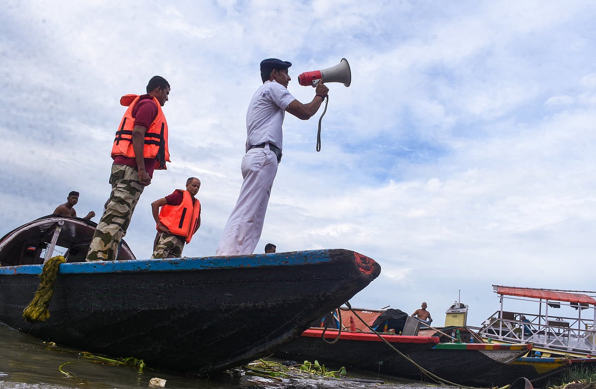 গঙ্গা নদীতে থাকা লোকজনকে নিরাপদ আশ্রয়ে সরে আসতে মাইকিং করছেন এক নৌ ট্রাফিক পুলিশ। গঙ্গা নদীর তীর, কলকাতা, বুধবার