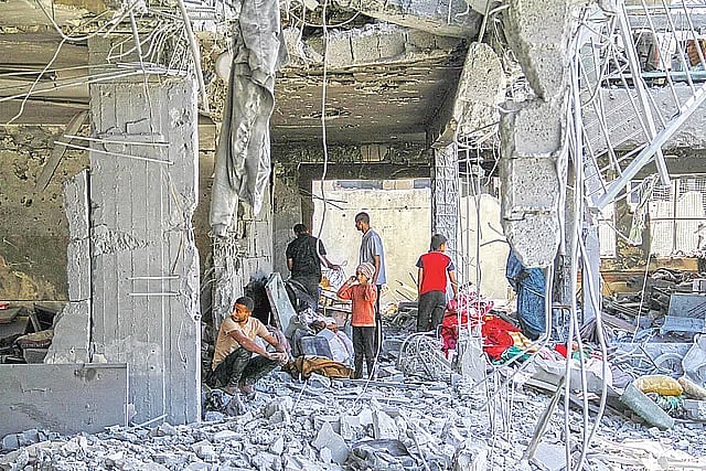 ইসরায়েলের হামলায় ধসে গেছে ভবন। ধ্বংসস্তূপে বসে আছেন কয়েকজন ফিলিস্তিনি। গাজা উপত্যকার জেইতুনে