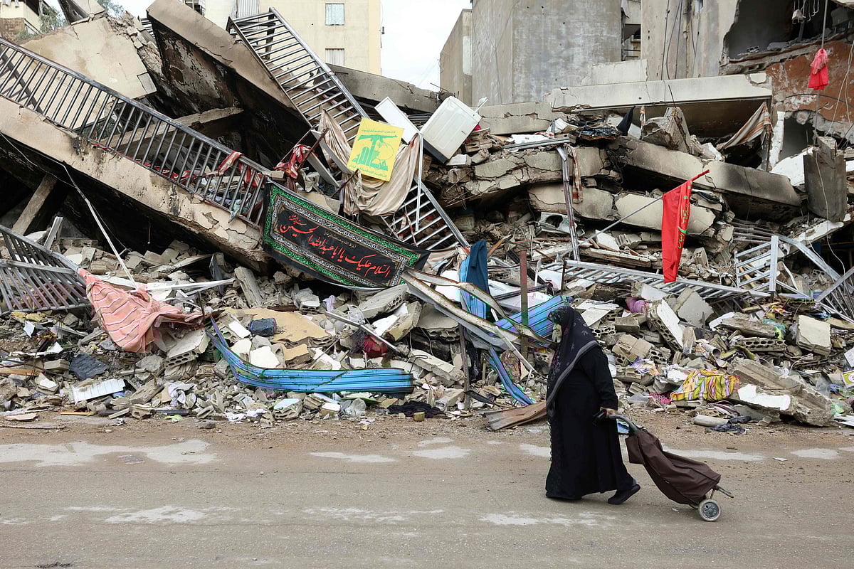 ইসরায়েলের হামলায় ধ্বংসস্তূপে পরিণত হয়েছে বাড়িঘর। পাশের রাস্তা দিয়ে হেঁটে যাচ্ছেন এক নারী। আজ বৃহস্পতিবার দক্ষিণ লেবাননের শিয়াহ এলাকায়