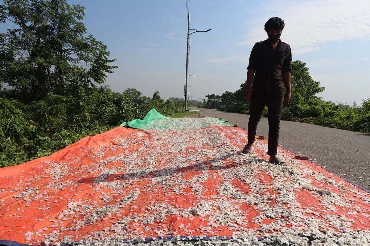 মাছের আঁশ শুকানোর কাজ করছেন এক যুবক। সম্প্রতি কুমিল্লার গোমতী নদীর বেড়িবাঁধ সড়কের পাশে