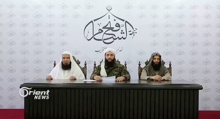 অজ্ঞাত স্থান থেকে কথা বলছেন আবু মোহাম্মদ আল-জোলানি (মধ্যে)। ছবিটি ২০১৬ সালের একটি ভিডিও থেকে নেওয়া