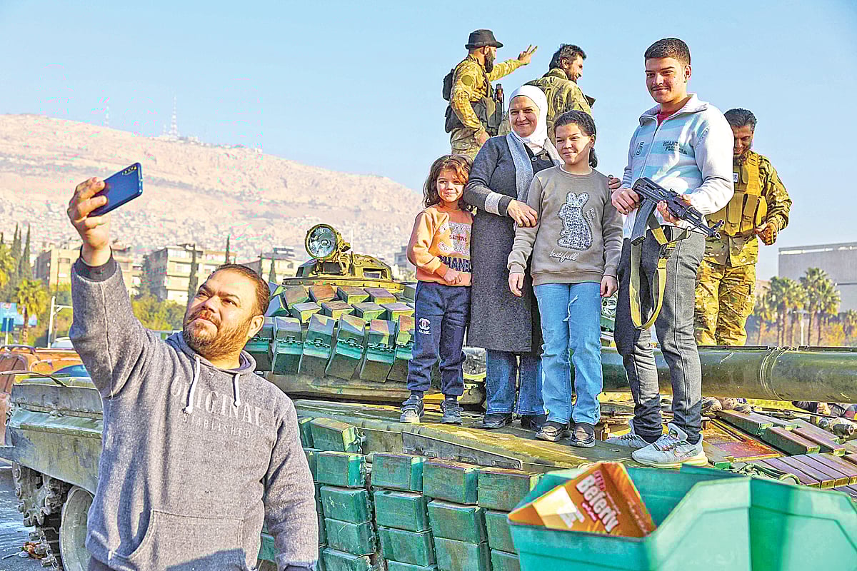 বিদ্রোহীদের ট্যাংকের ওপর পরিবারের সদস্যরা। সামনে দাঁড়িয়ে তাঁদের সঙ্গে সেলফি তুলছেন এক ব্যক্তি। এভাবেই প্রেসিডেন্ট বাশার আল–আসাদের পতন উদ্‌যাপন করছেন তাঁরা। গতকাল সিরিয়ার রাজধানী দামেস্কে