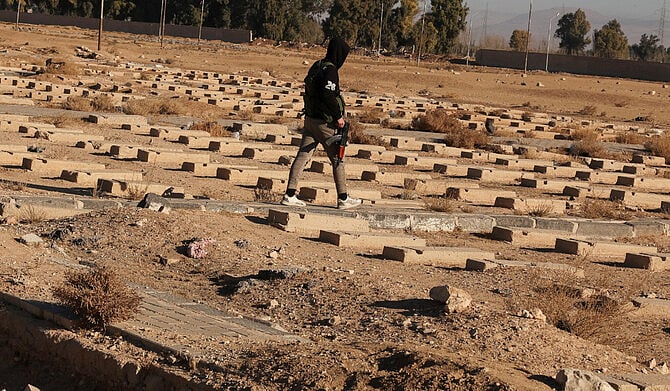 সিরিয়ায় বাশার আল–আসাদের আমলের একটি গণকবরের মাঝখান দিয়ে হেঁটে যাচ্ছেন এক বিদ্রোহী যোদ্ধা। ১৫ ডিসেম্বর, নাজহা, সিরিয়া