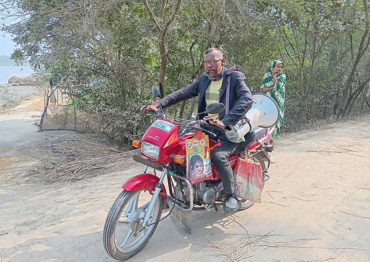 মোটরসাইকেলে চড়ে মাইকিং করছেন আয়ুব আলী সানা। গত বুধবার দুপুরে খুলনার দাকোপ উপজেলার কামারখোলা এলাকায় পানি উন্নয়ন বোর্ডের বেড়িবাঁধ সড়কে