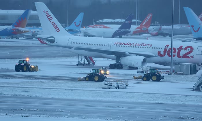 রানওয়েতে জমে থাকা তুষার ট্রাক্টর দিয়ে পরিষ্কার করা হচ্ছে। ৪ জানুয়ারি, ২০২৪, যুক্তরাজ্যের ম্যানচেস্টার বিমানবন্দরে