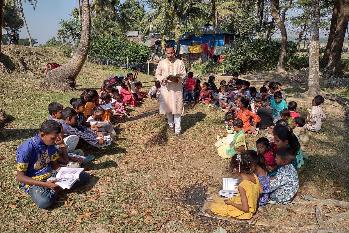চট্টগ্রামের মিরসরাই উপজেলার সাহেরখালী ইউনিয়নের গজারিয়া গ্রামের উপকূলীয় বেড়িবাঁধ এলাকায় ‘গাছতলার বিদ্যালয়ে’ শিশুদের পড়াচ্ছেন ইকবাল হোসেন। সম্প্রতি তোলা