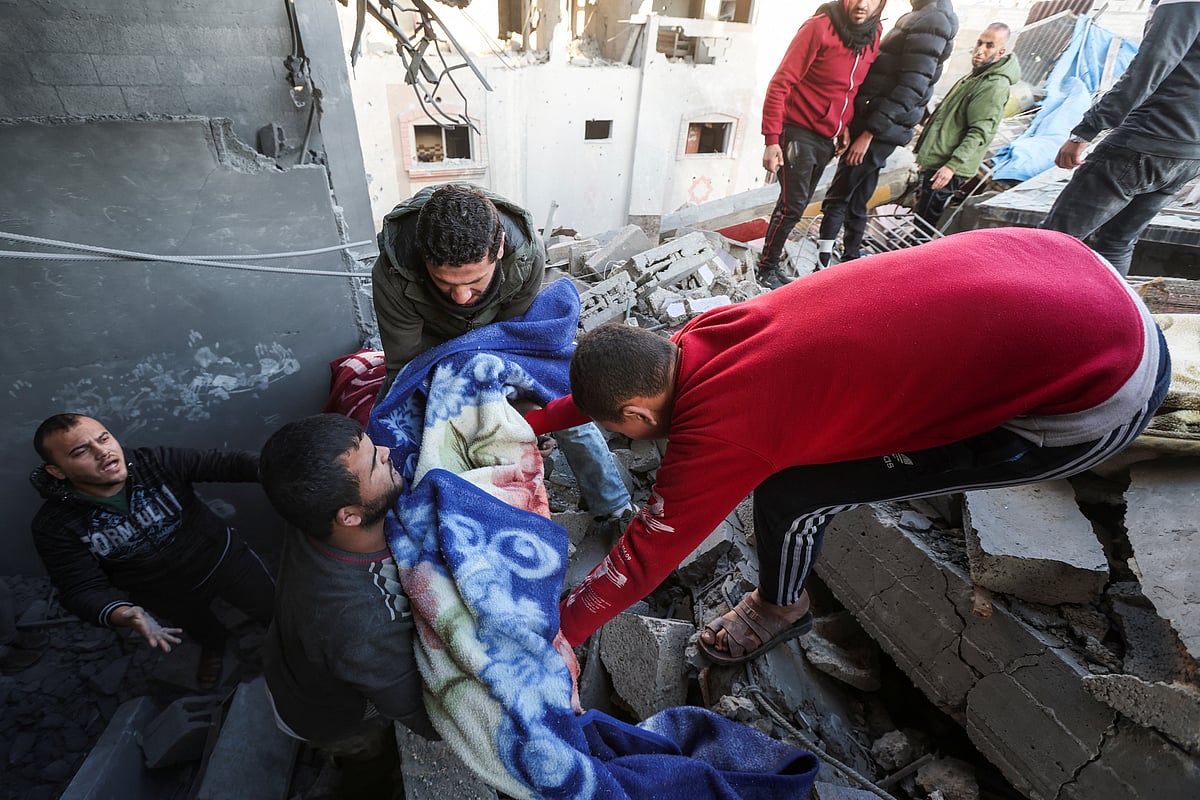 ইসরায়েলি হামলায় নিহত এক শিশুর মরদেহ উদ্ধার করছে লোকজন। আজ বৃহস্পতিবার গাজায়