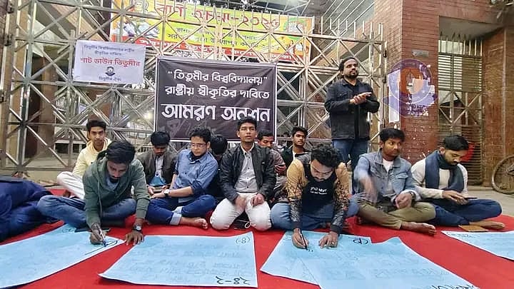 কলেজের মূল ফটকের সামনে ‘তিতুমীর বিশ্ববিদ্যালয় রাষ্ট্রীয় স্বীকৃতির দাবিতে’ পাঁচজন শিক্ষার্থী অনশনে বসেছেন