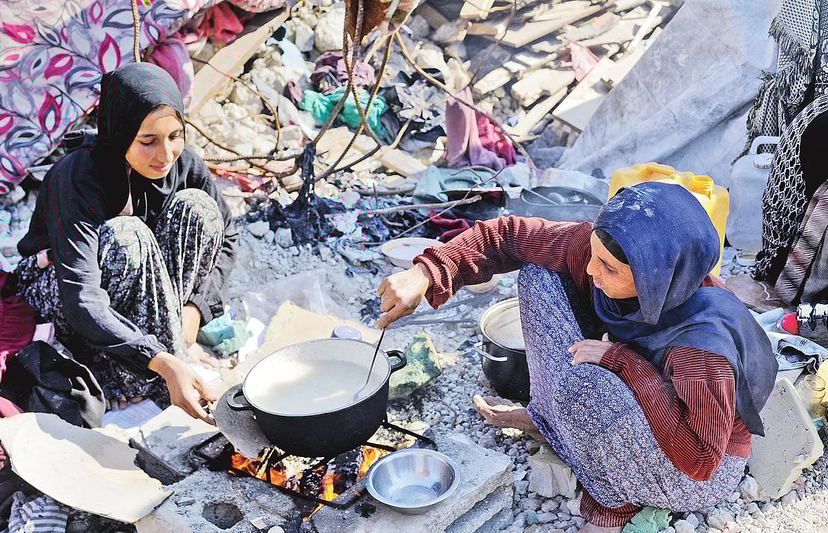 মানাল আল-হার্শ (ডানে) একসময় যে ভবনে পরিবারসহ থাকতেন, ইসরায়েলি বাহিনী হামলা চালিয়ে তা গুঁড়িয়ে দিয়েছে। সেই ভবনের ধ্বংসস্তুূপের ওপর রান্না করছেন উদ্বাস্তু এই নারী। রান্নায় সহযোগিতা করছেন তাঁর মেয়ে। বুধবার উত্তর গাজার জাবালিয়ায়