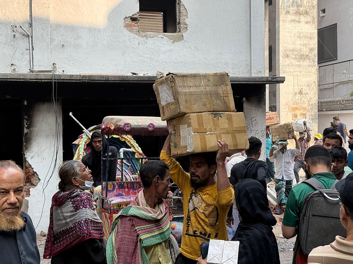 ঢাকার ধানমন্ডি ৩২ নম্বরে শেখ মুজিবুর রহমানের বাড়ির পেছনে ছয়তলা ভবন থেকে বইয়ের কার্টন নিয়ে যাচ্ছেন একজন। আজ বৃহস্পতিবার বেলা ১১টার দিকে