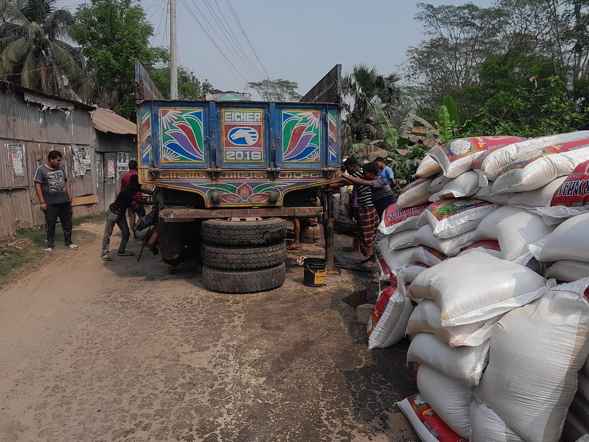 চালের বস্তাগুলো নামিয়ে স্থানীয় শ্রমিকদের সাহায্যে সড়ক থেকে ট্রাকটি সরিয়ে নেওয়া হচ্ছে। সোমবার বিকেলে শরীয়তপুর সদর উপজেলার হুগলি এলাকায়