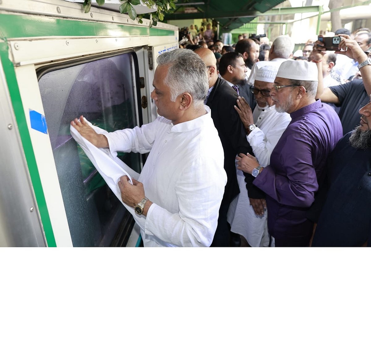 পরম মমতায় বাবা সৈয়দ মঞ্জুর এলাহীর মরদেহ বহনকারী গাড়ির গ্লাস নিজের পাঞ্জাবি দিয়ে মুছে দিচ্ছেন ছেলে সৈয়দ নাসিম মঞ্জুর।