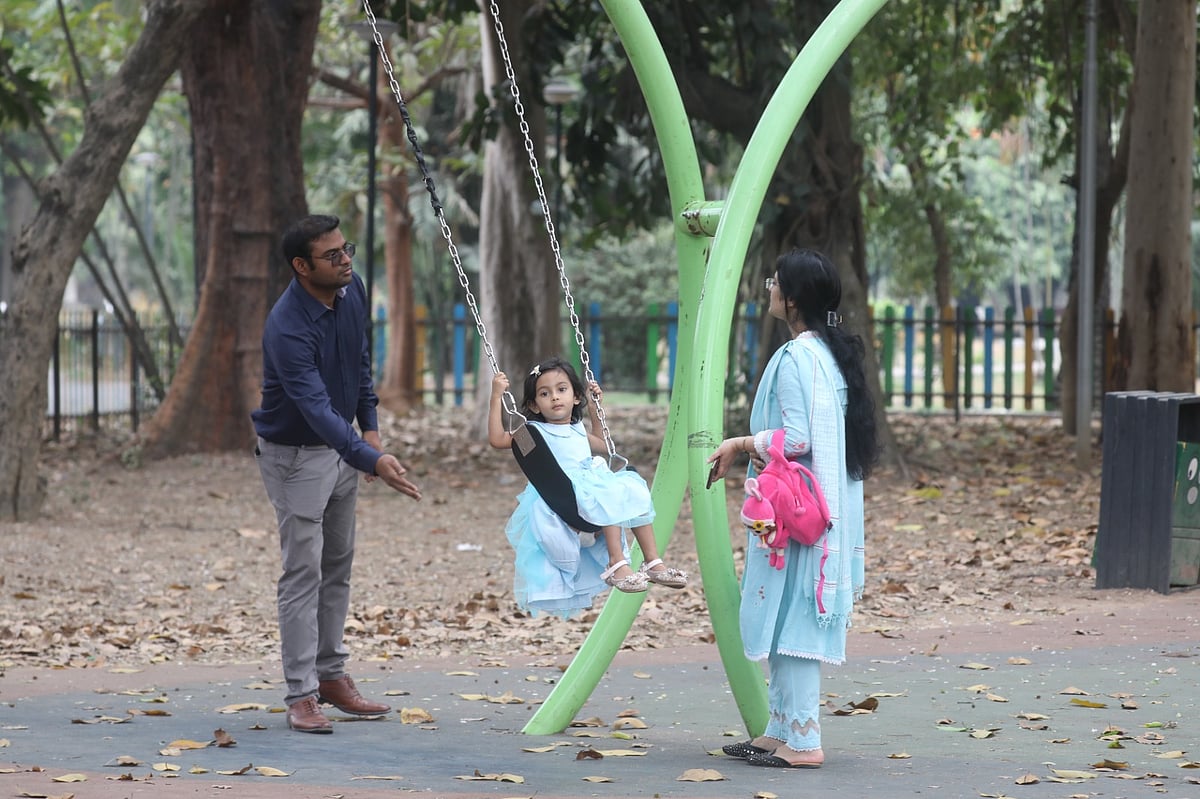 রমনা পার্কের শিশুচত্বরের দোলনায় ছোট্ট আরশী খন্দকার। দোল দিচ্ছেন বাবা রবিউল ইসলাম। সামনে সন্তানের ব্যাগ হাতে দাঁড়িয়ে মা সামিয়া ইয়াসমিন