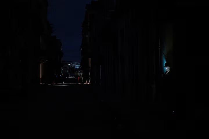 কিউবার রাজধানী হাভানা অন্ধকারে। এর মধ্যেই মোবাইল ব্যবহার করছেন এক ব্যক্তি