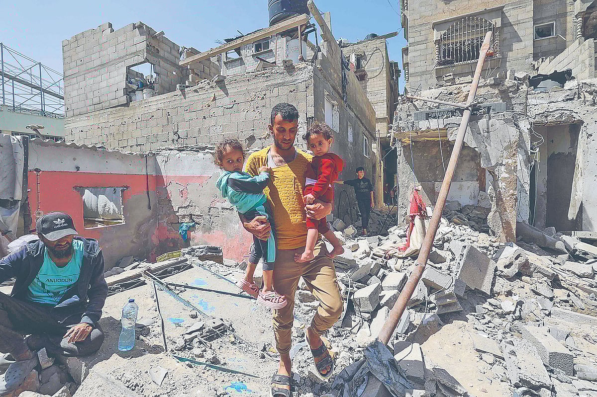 ইসরায়েলি হামলায় ধ্বংসস্তূপে পরিণত হওয়া ভবনের ভেতর দিয়ে দুই শিশুকে সরিয়ে নিচ্ছেন এক ফিলিস্তিনি। গতকাল দক্ষিণ গাজার খান ইউনিসে