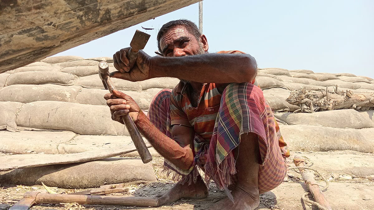 খুলনার দাকোপ উপজেলার শিবসা নদীর তীরে কালাবগী গ্রামের বেড়িবাঁধের নিচে নৌকা তৈরি করছেন জামশেদ গাজী