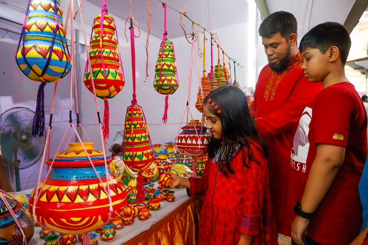 মাটির তৈরি তৈজসপত্র দেখছে পরিবারের সঙ্গে মেলায় ঘুরতে আসা এই শিশু। ঢাকা, ১৫ এপ্রিল