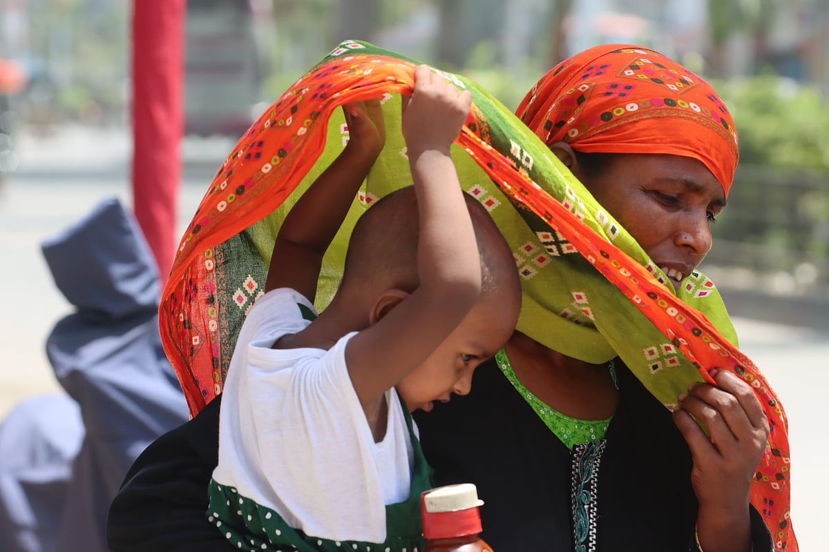মায়ের আঁচলে রোদের তাপ থেকে বাঁচার চেষ্টা করছে শিশুটি। আজ দুপুরে রাজশাহী নগরের শহীদ এ এইচ এম কামারুজ্জামান চত্বরে (রেলগেট) তোলা