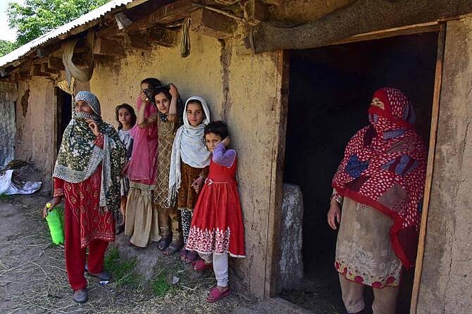 পাকিস্তান–নিয়ন্ত্রিত কাশ্মীরের একটি গ্রামের কয়েকজন বাসিন্দা নিজেদের বাড়ির সামনে দাঁড়িয়ে আছেন