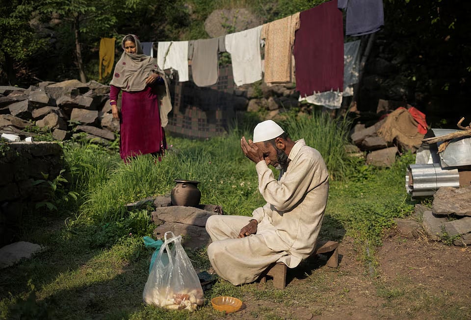 বাড়ির বাইরে খাবার তৈরিতে ব্যস্ত কাশ্মীরের বাসিন্দা আসাদুল্লাহ মির। সেদিকে তাকিয়ে আছেন তাঁর স্ত্রী। নিয়ন্ত্রণরেখার কাছে তিলাওয়ারি গ্রাম, উরি, উত্তর কাশ্মীর, ১ মে ২০২৫