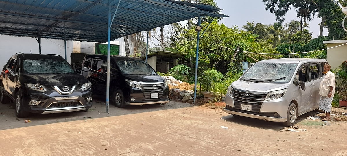 বাড়ির সামনে কাচ ভাঙা অবস্থায় পড়ে রয়েছে তিনটি গাড়ি। আজ রোববার সকালে তোলা