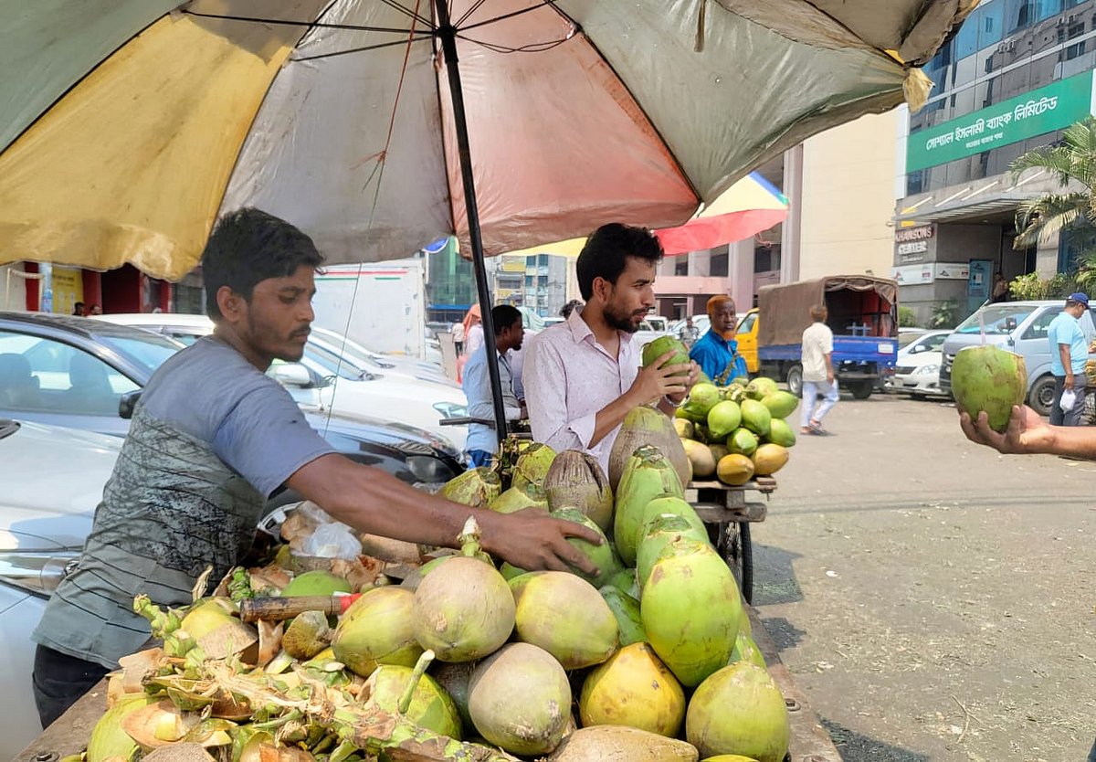 রাজধানীর কারওয়ান বাজারে তীব্র গরমে ডাবের পানি পান করছেন একজন পথচারী।